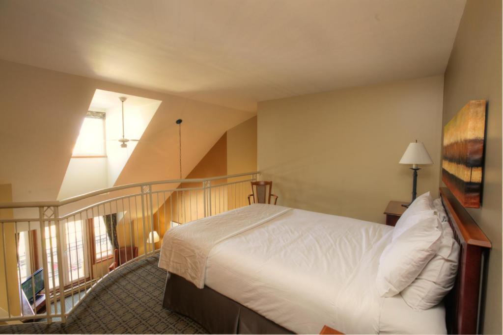 a bedroom with a white bed and a staircase at Place Saint Bernard Mont Tremblant in Mont-Tremblant