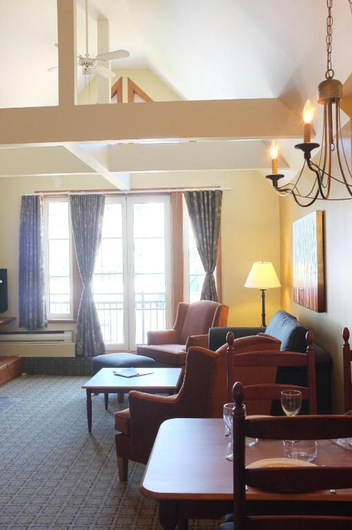a living room with couches and tables and windows at Place Saint Bernard Mont Tremblant in Mont-Tremblant