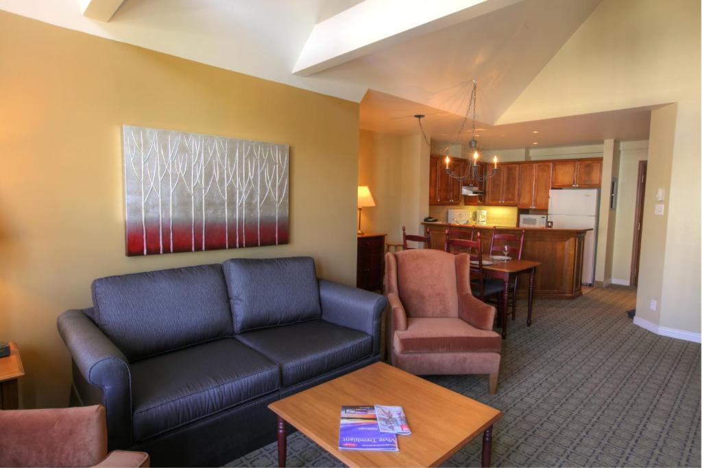 a living room with a couch and a kitchen at Place Saint Bernard Mont Tremblant in Mont-Tremblant