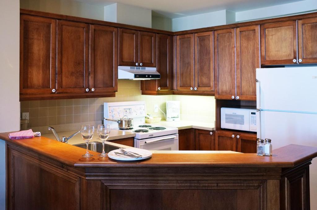 a kitchen with wooden cabinets and a counter with wine glasses at Place Saint Bernard Mont Tremblant in Mont-Tremblant