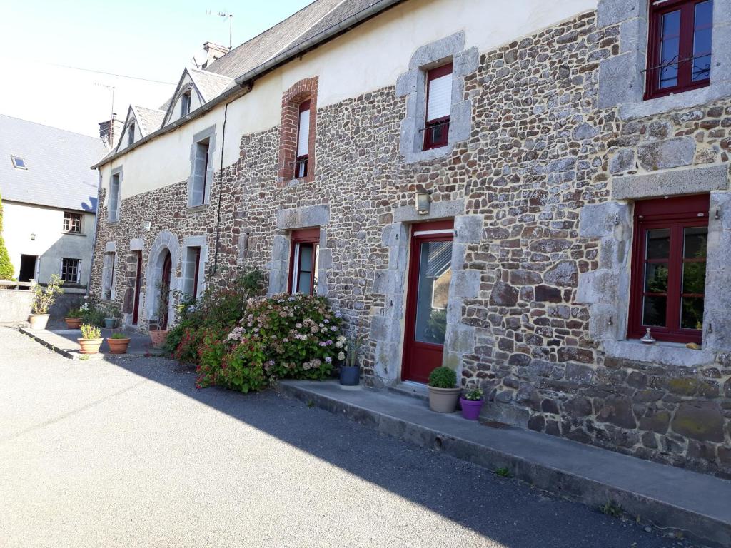 een oud stenen gebouw met rode deuren en ramen bij Chambres d'hôtes Au Hameau in Le Mesnil-Aubert