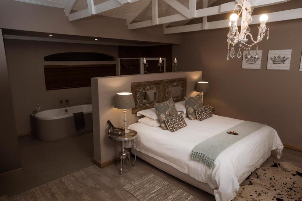 a bedroom with a bed and a bath tub and a chandelier at Klip en Kristal Guest House in Bela-Bela