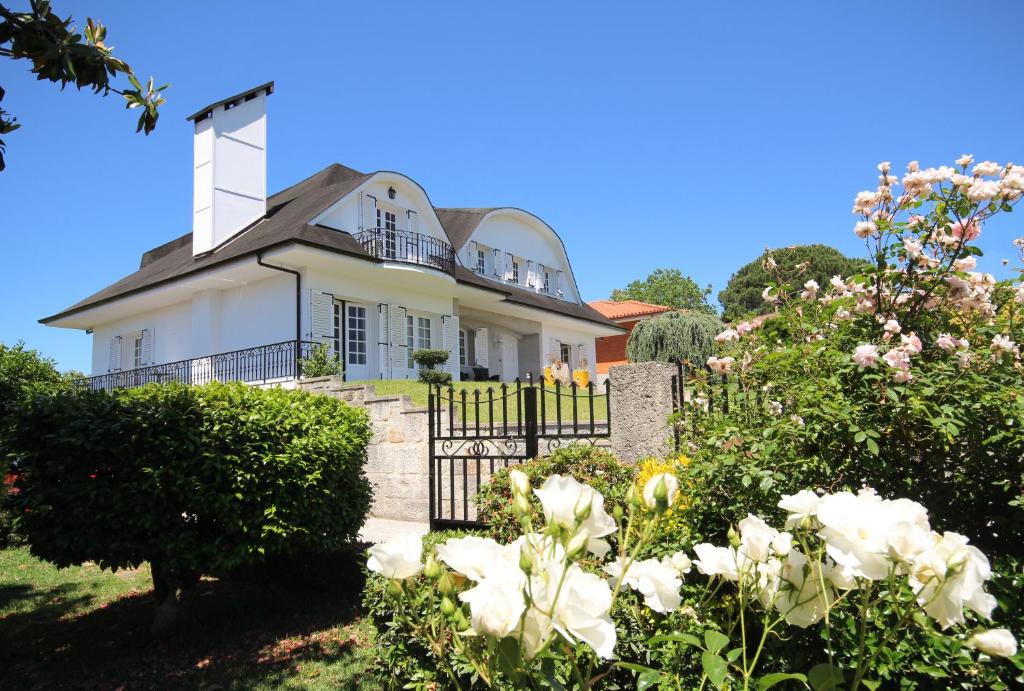 a white house with a gate and flowers at B&B Villa Branca Barreiros AL98139 in Barreiros