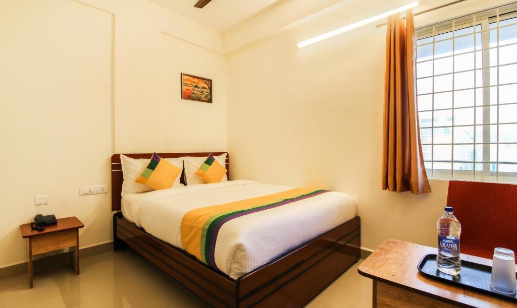 a bedroom with a bed and a desk and a window at Itsy By Treebo - Riyas Grand in Tirupati