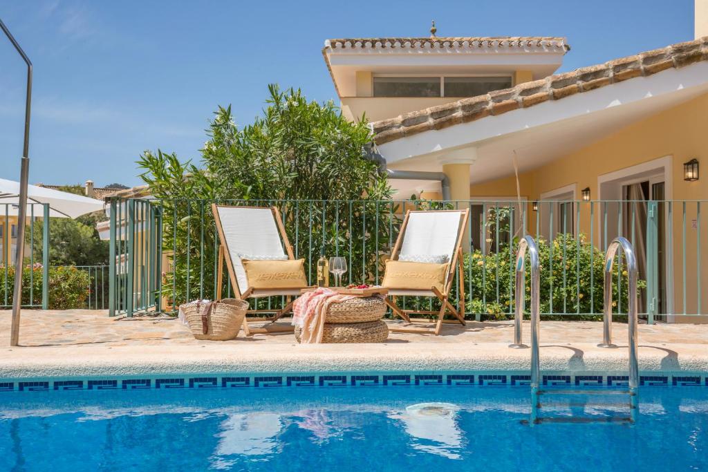 une villa avec une piscine et deux chaises dans l'établissement Villa Olympus. Piscina Privada. La Manga Club, à Atamaría