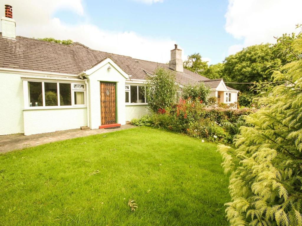 a white house with a yard with a grass yard at Bryn Ffynnon in Benllech