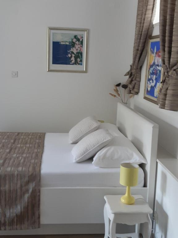 a white bed with a yellow lamp on a side table at Studio Marin in Dubrovnik