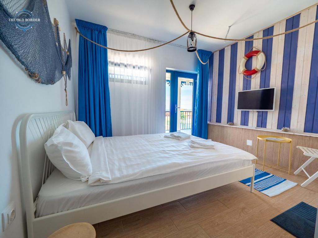 a bedroom with a bed with blue curtains and a tv at The Old Border in Vama Veche