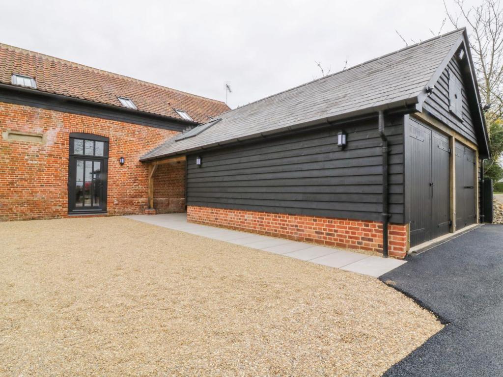 a brick building with a black garage at Grange Barn in Hessett