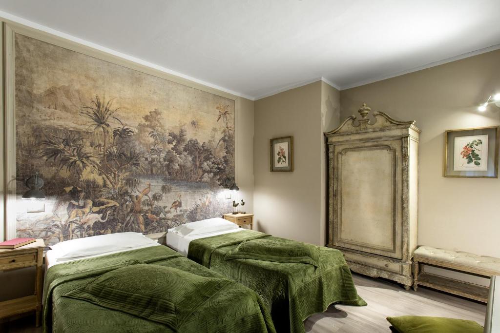 two beds in a room with a painting on the wall at Hotel Del Borgo in Bologna