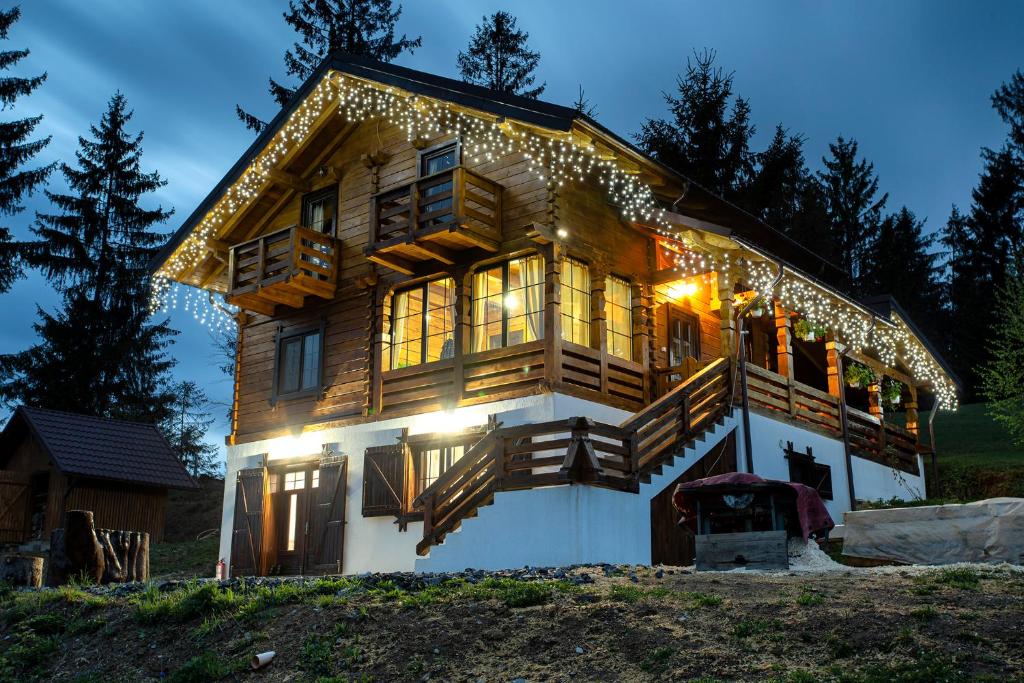 a large wooden house with christmas lights on it at Tulean Cabin in Săcel