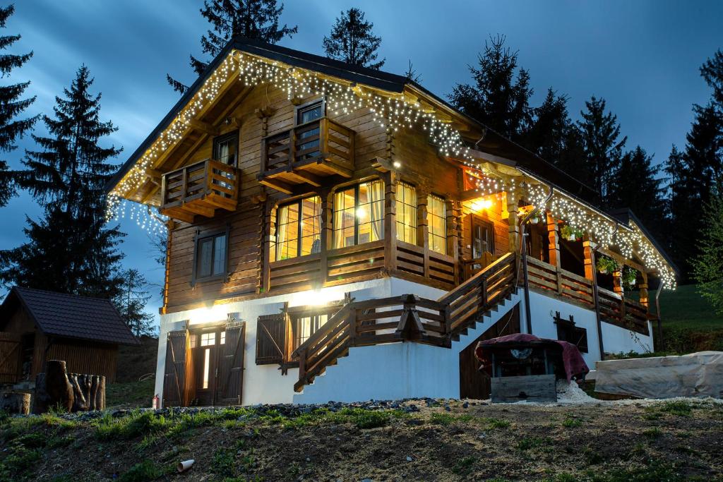 Una gran casa de madera con luces de Navidad. en Tulean Cabin, en Săcel