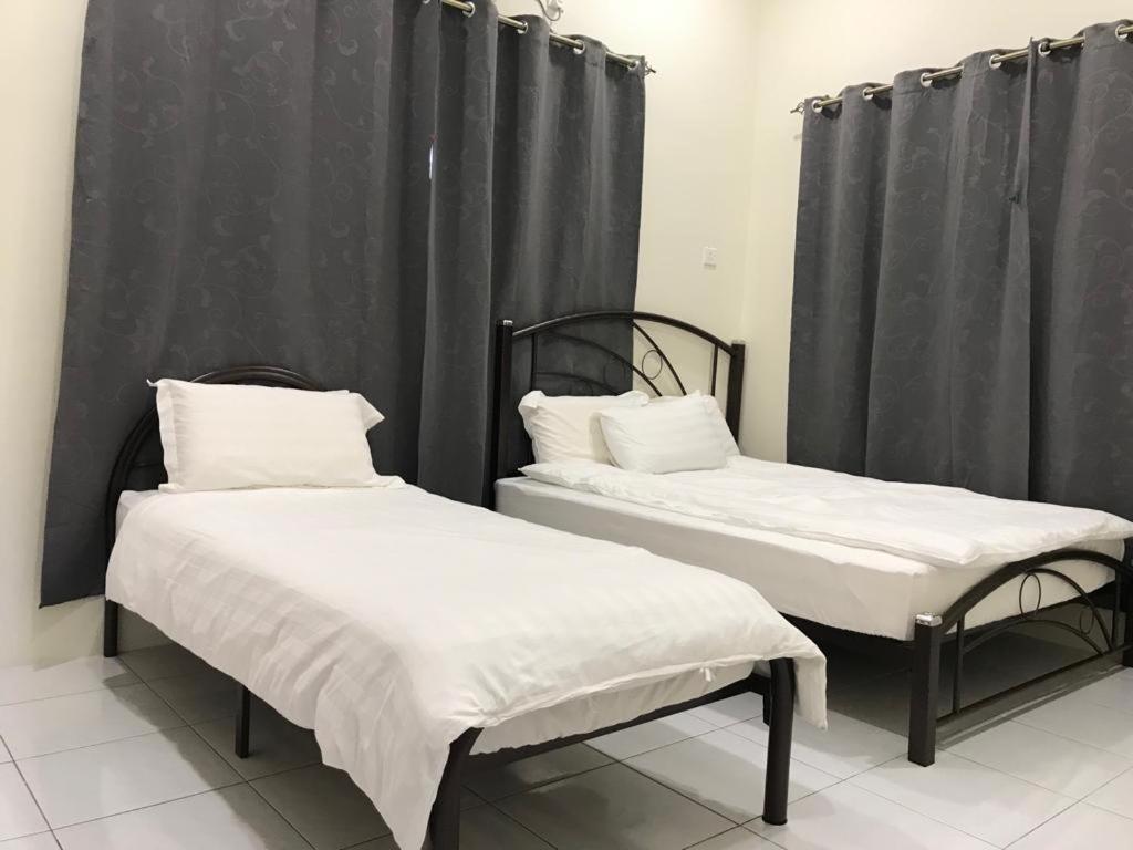 two beds in a room with black curtains at 1248 Cozy Home in Ipoh