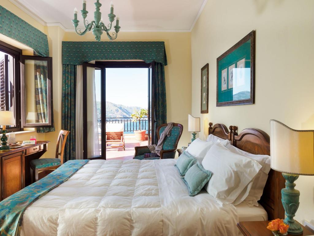 a bedroom with a large bed and a balcony at Hotel Sirius in Taormina