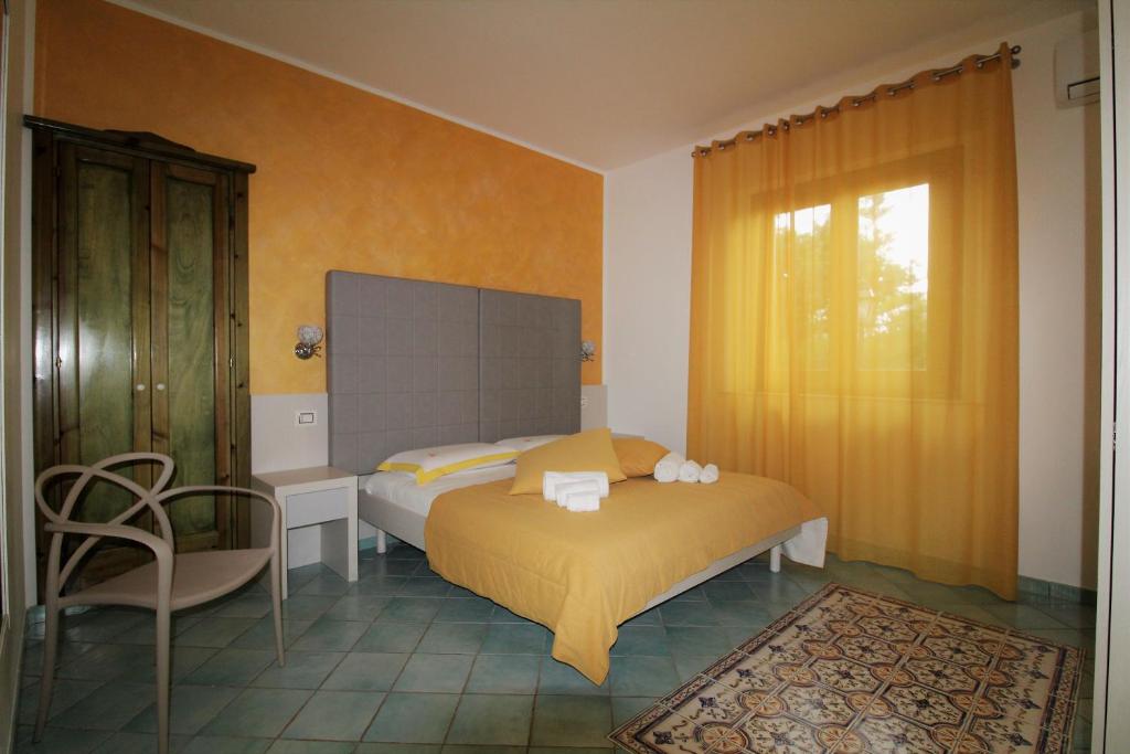 a bedroom with a bed and a chair and a window at B&B Villa Bea in San Vito lo Capo