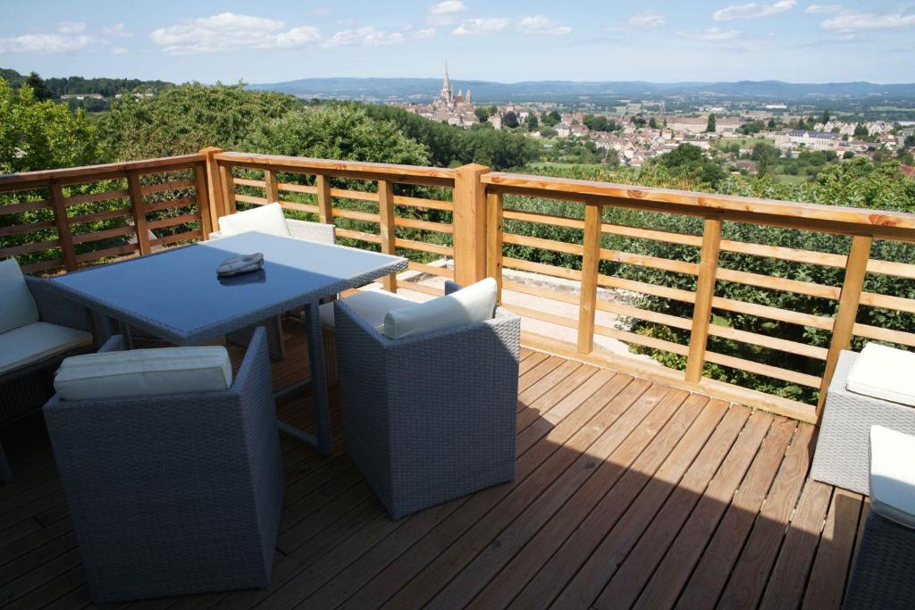 une terrasse en bois avec une table et des chaises. dans l'établissement Chambres d'hotes à Autun, à Autun