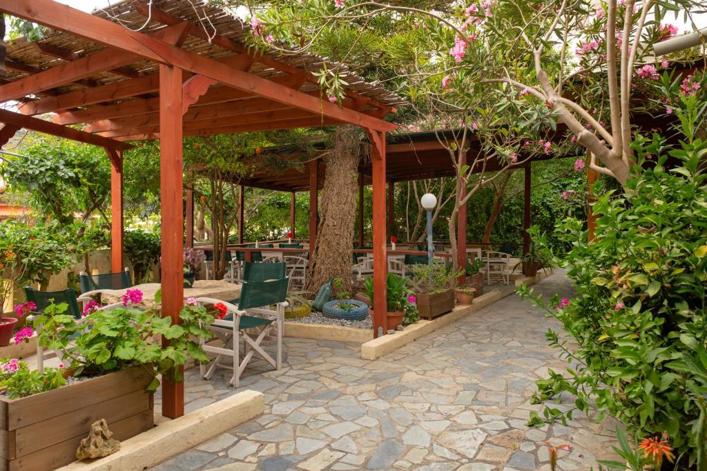 a patio with a wooden pergola with chairs and plants at Apartments and Studios Xenophon in Matala