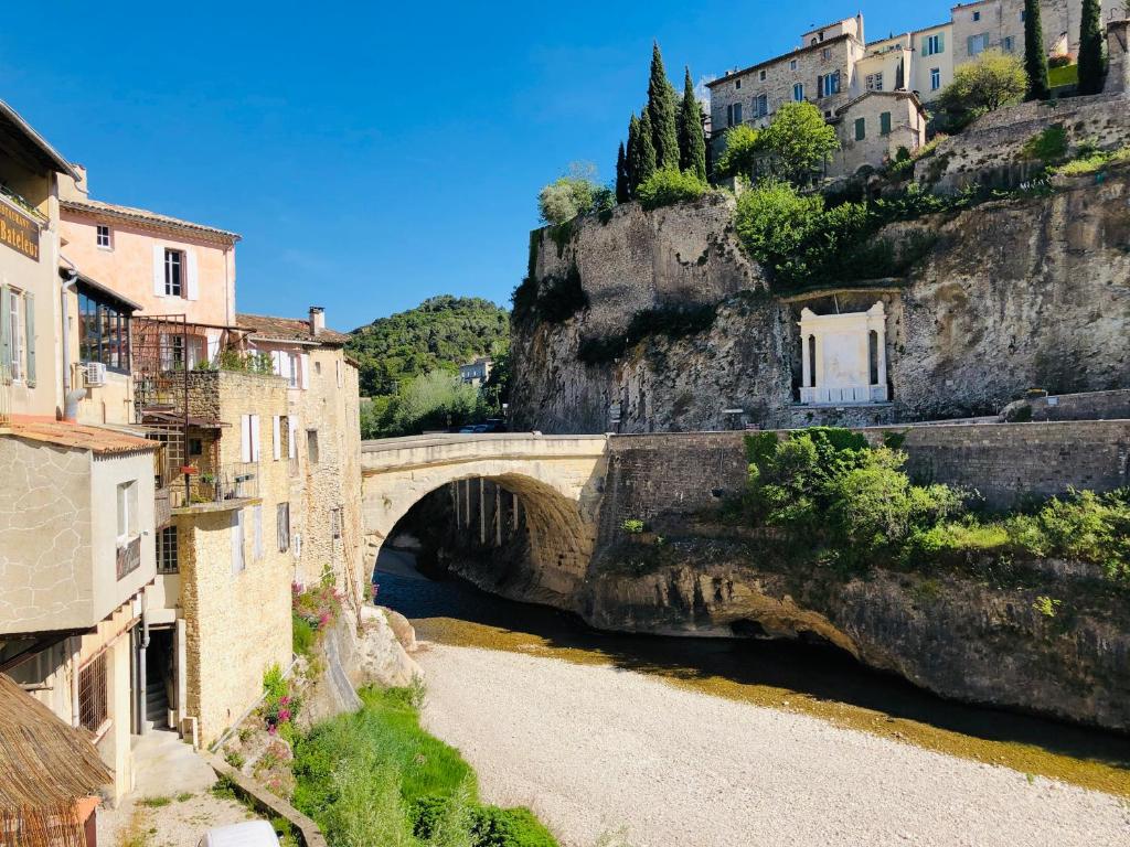 un pont sur une rivière dans une ville avec des bâtiments dans l'établissement Apartment Pont Romain, à Vaison-la-Romaine