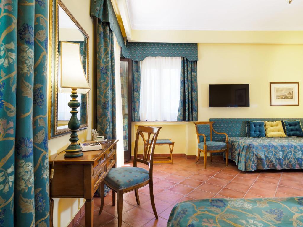 a hotel room with a bed and a desk at Hotel Sirius in Taormina
