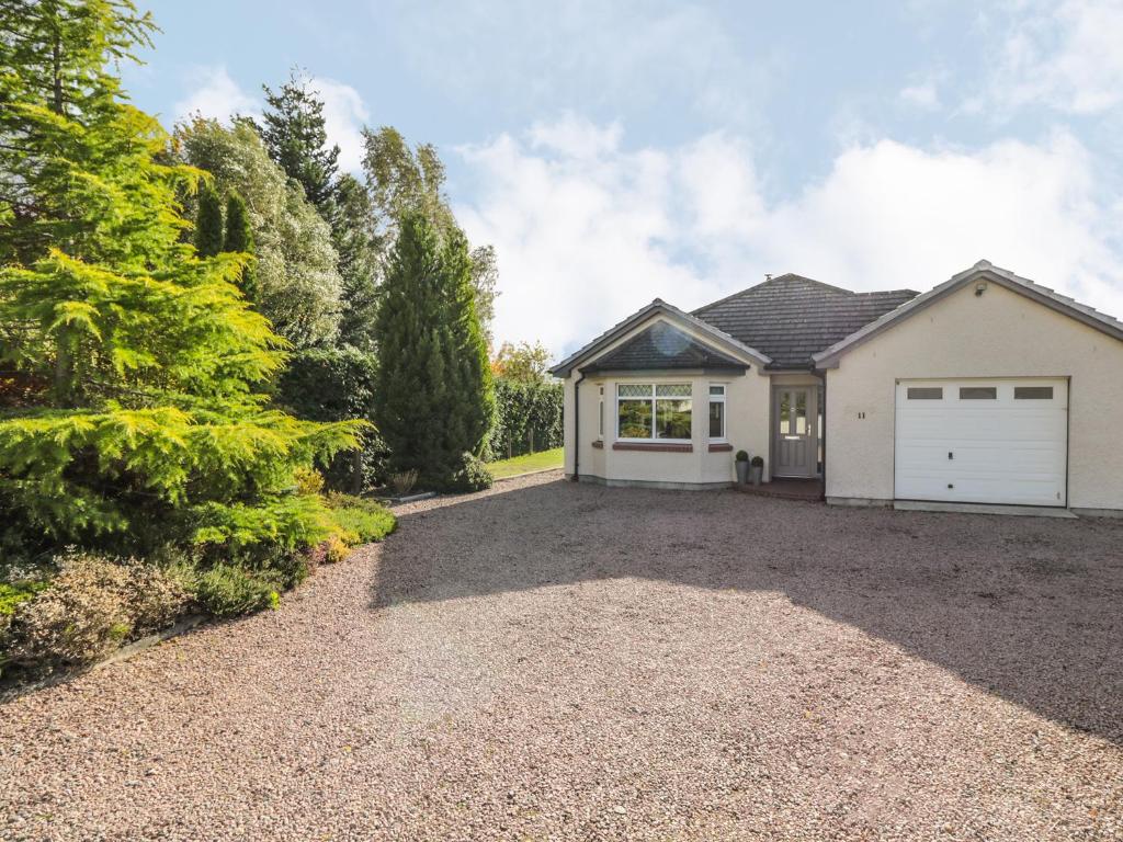 a house with a white garage and a driveway at Number 11 in Beauly