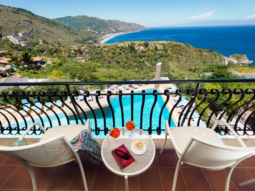 a balcony with a table and chairs and the ocean at Hotel Sirius in Taormina