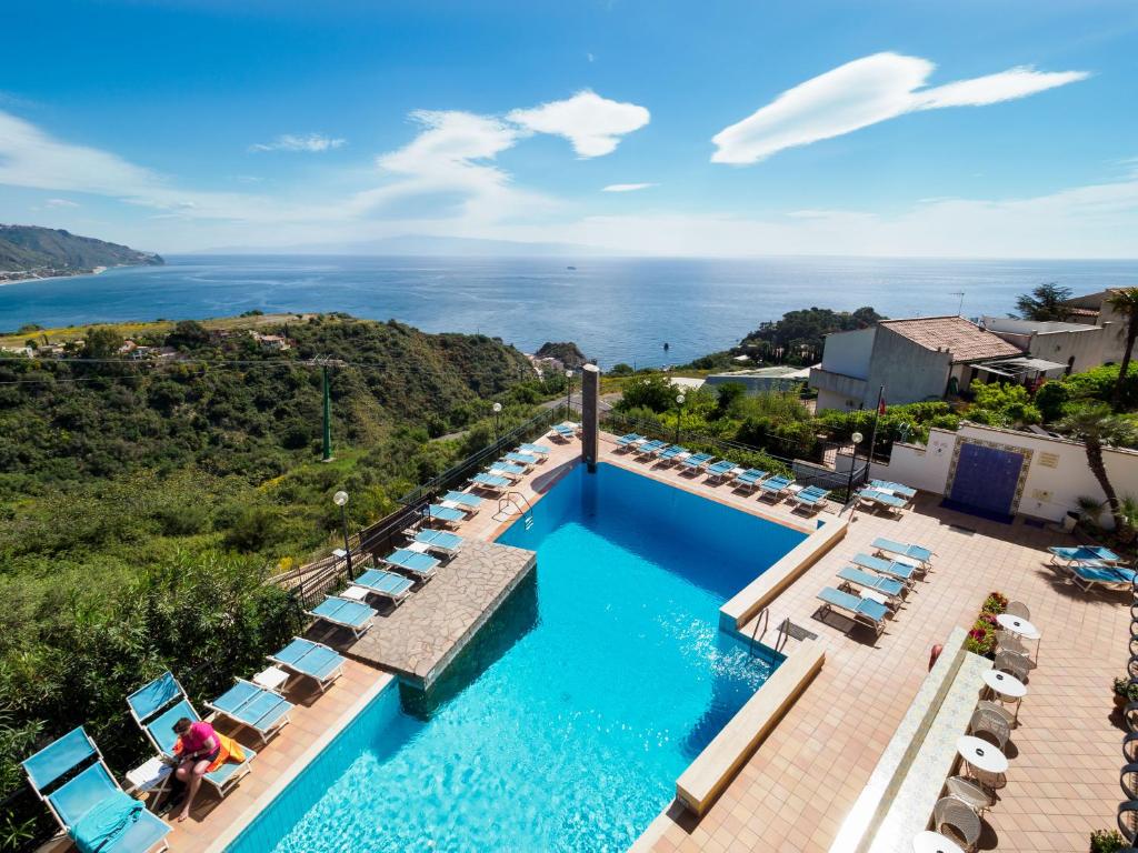 an aerial view of a pool with chairs and the ocean at Hotel Sirius in Taormina
