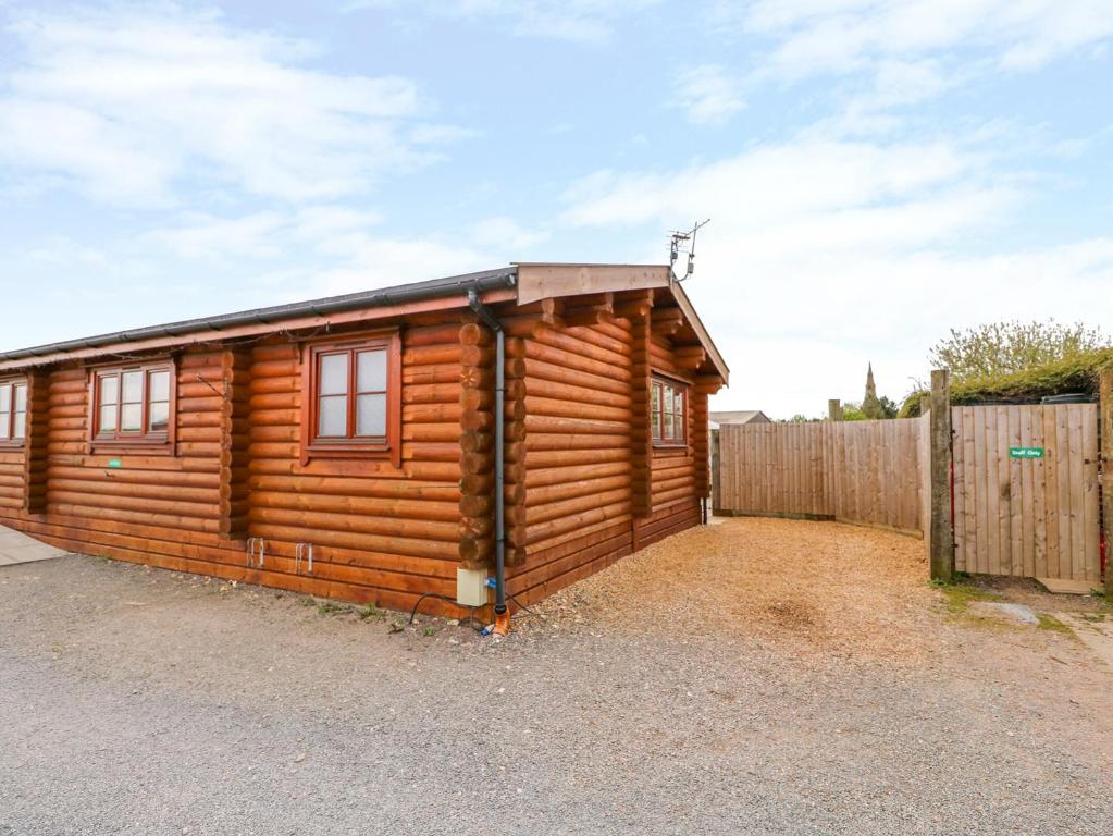 una cabaña de madera con una valla delante en Church View en Oakham