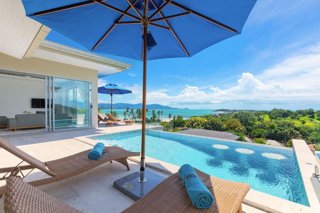 a villa with a swimming pool and an umbrella at Single Level BEACHSIDE VILLA - BB2 - at BAYSIDE LUXURY VILLAS Samrong Bay Beach, 3 BED 4 BATH, SEA and SUNSET VIEWS, only 200m walk to the Beach in Bang Rak Beach