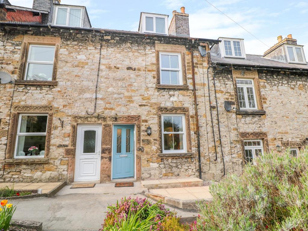 an old stone house with a blue door at Wyebrow Cottage in Bakewell