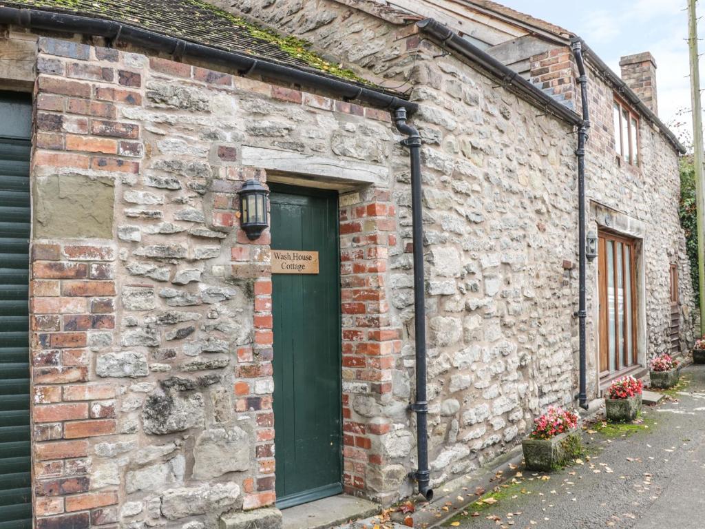 ein altes Backsteingebäude mit grüner Tür in der Unterkunft Wash House Cottage in Much Wenlock