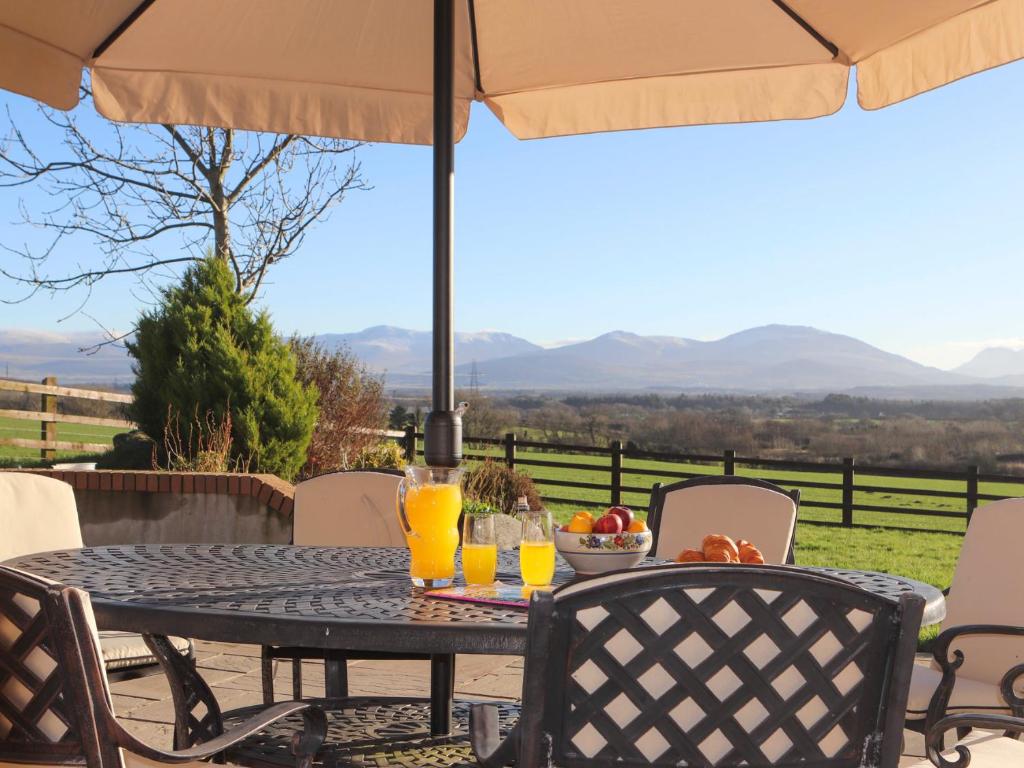 a table with orange juice and a bowl of fruit on it at Dol Fraint in Llanfairpwllgwyngyll