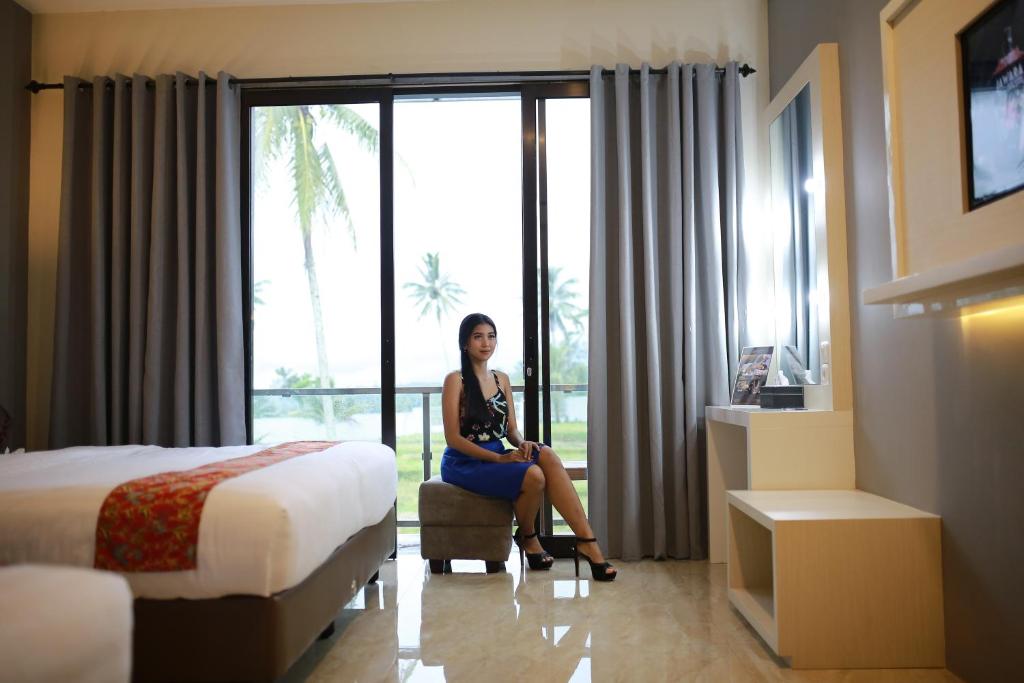 Grand Harvest Resort & Villas في بانيووانجى: امرأة جالسة على كرسي في غرفة الفندق