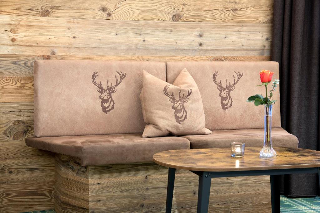 a couch with two pillows and a table with a rose at Hotel Bergland in Pertisau