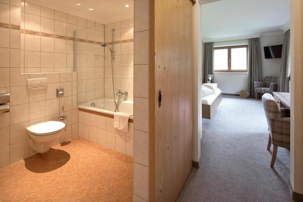 a bathroom with a toilet and a bath tub at Hotel Bergland in Pertisau