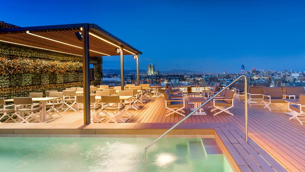 eine Dachterrasse mit einem Pool, Tischen und Stühlen in der Unterkunft Majestic Hotel & Spa Barcelona GL in Barcelona