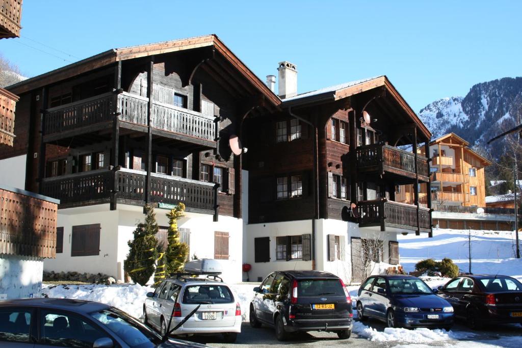 duży budynek z samochodami zaparkowanymi na parkingu w obiekcie Bachhüs BA1 w mieście Blatten bei Naters