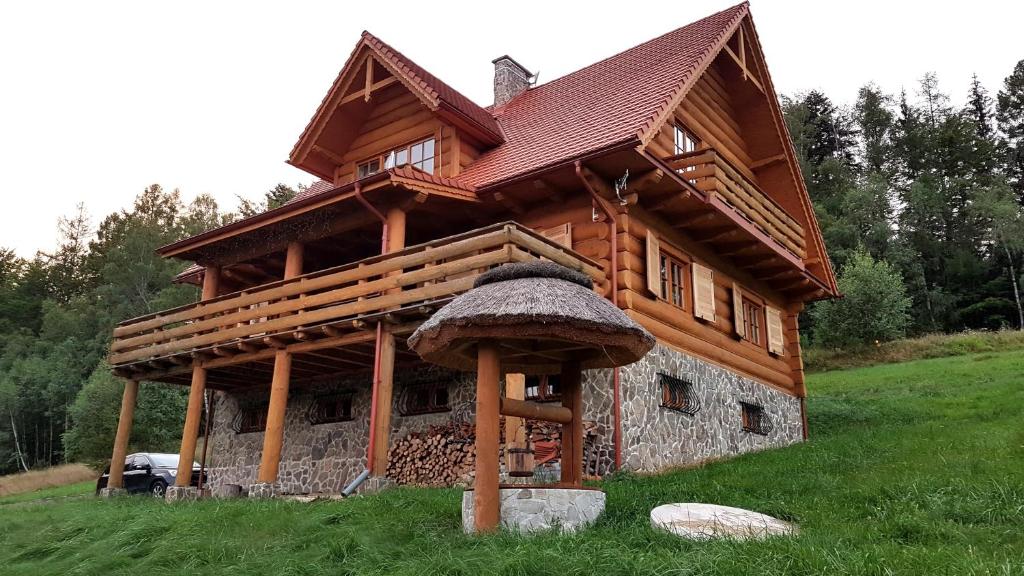 a log cabin with a roof on a green field at Dom Trzech Braci in Lądek-Zdrój