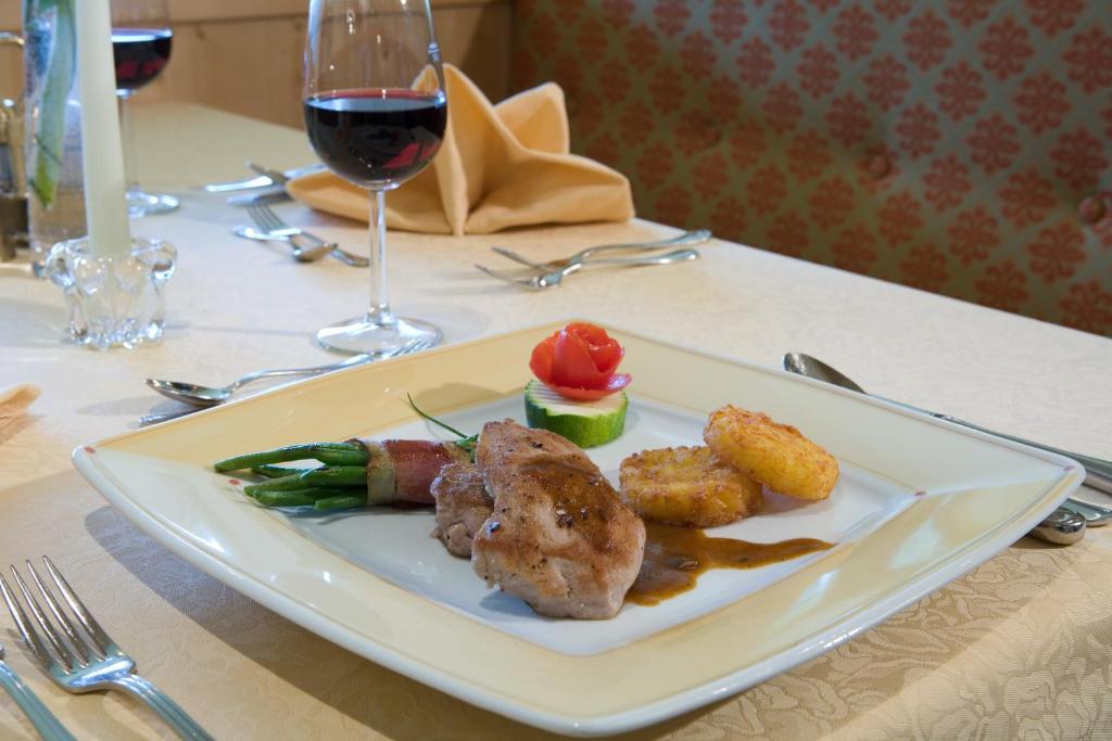 a plate of food on a table with a glass of wine at Hotel Bergland in Pertisau