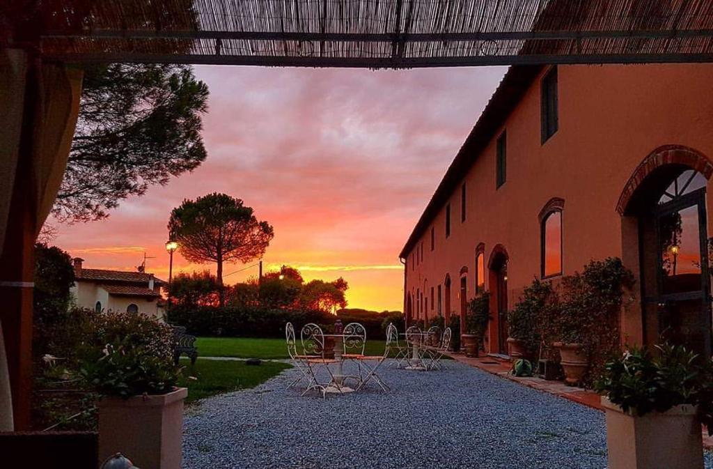 a group of chairs sitting outside of a building with a sunset at La Magnifica B&B in Fauglia