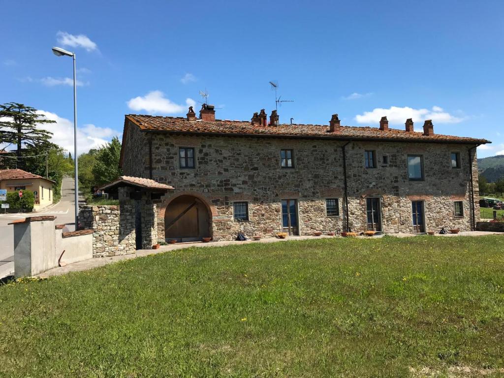 uma velha casa de pedra com um campo de relva em frente em Casa Adrigagi Firenze e La Via degli Dei em Pratolino