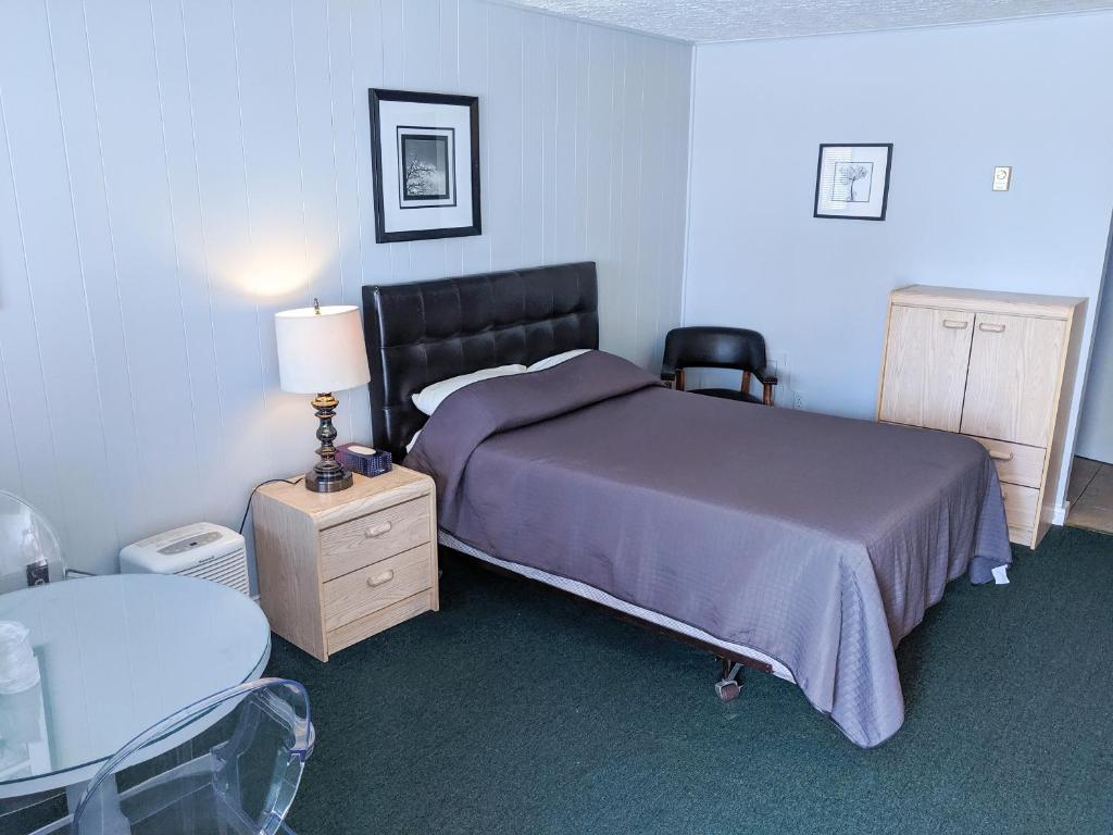 a bedroom with a bed and a table and a chair at Skyline Motel in Fredericton