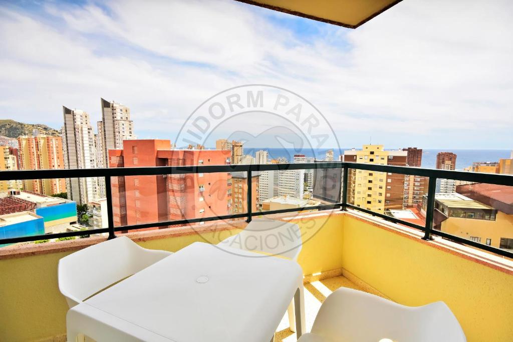 a balcony with white chairs and a view of the city at Apartamentos Paraíso Centro - BenidormParaíso in Benidorm