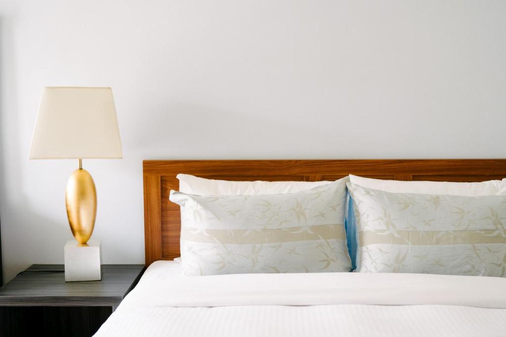 a bedroom with a white bed with a lamp and pillows at He Sen B&B in Kenting