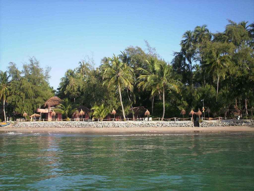 Una playa con palmeras y un elefante. en Pousada Doze Cabanas en Japaratinga