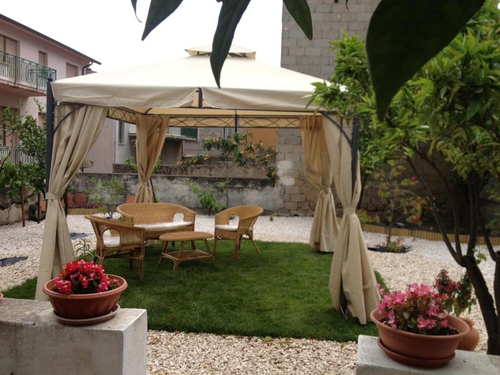 een tuinhuisje met stoelen en een tafel in de tuin bij b&b Mundè in Oliena