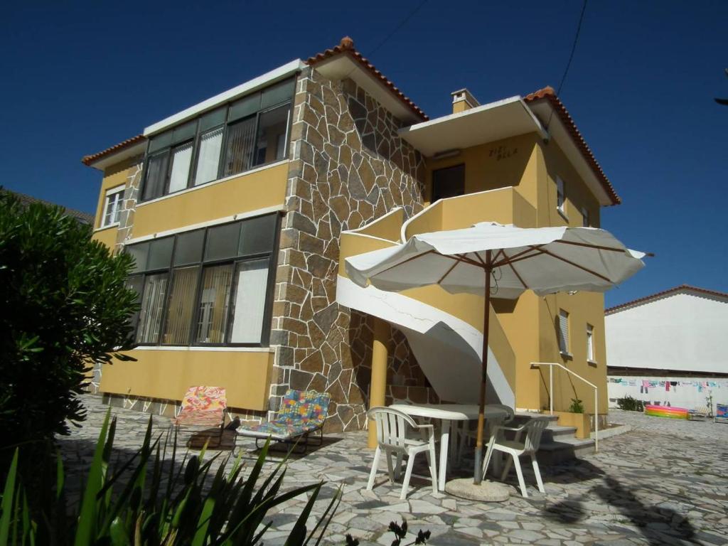 a yellow building with a table and an umbrella at Casa Zizi Bela in Lourinhã