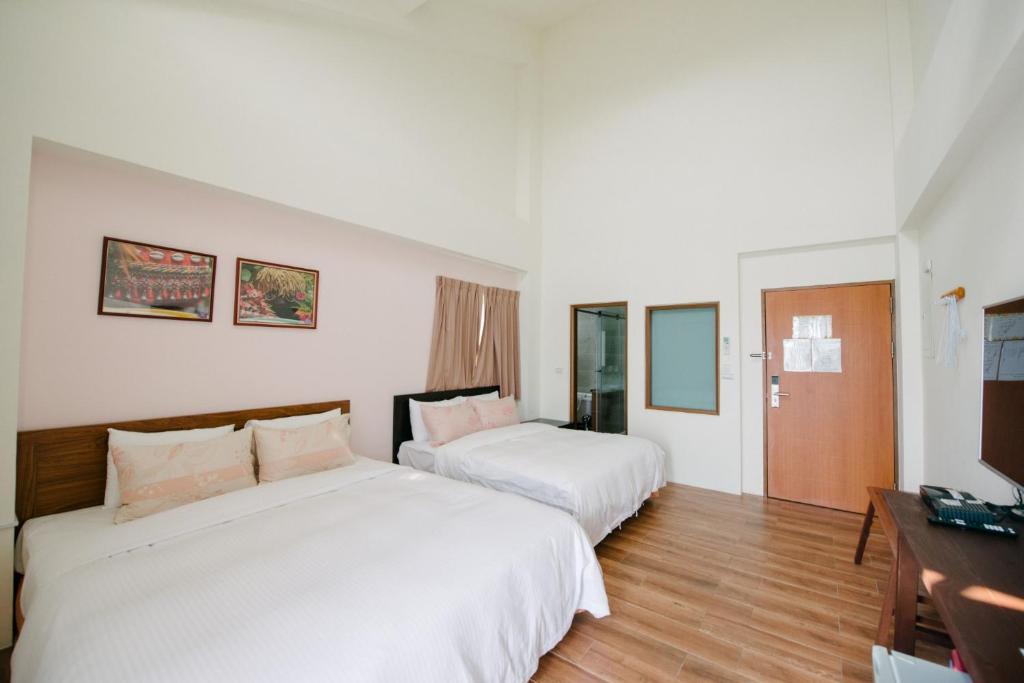 a hotel room with two beds and a television at He Sen B&B in Kenting