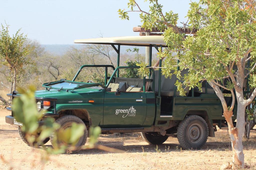 a green jeep parked in the dirt near a tree at Greenfire Game Lodge in Balule Game Reserve