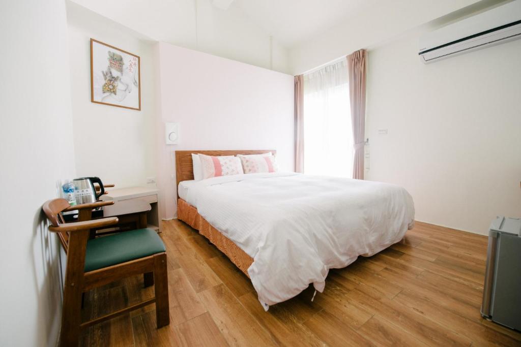 a bedroom with a bed and a desk and a window at He Sen B&B in Kenting