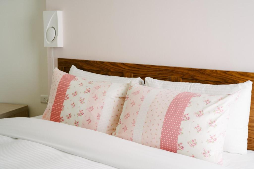 a bed with pink and white pillows on it at He Sen B&B in Kenting